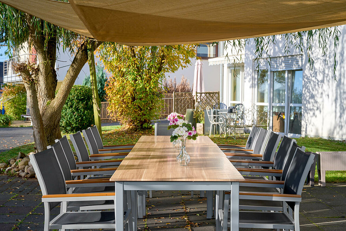 Terrasse mit Sonnensegel und langem Tisch