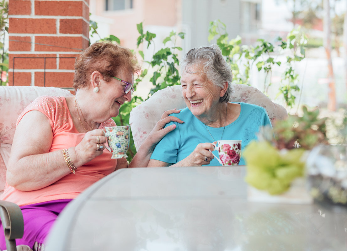 Seniorinnen trinken Tee auf der Terrasse einer Alloheim Senioren-Residenz