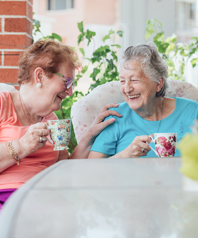 Seniorinnen trinken Tee auf der Terrasse einer Alloheim Senioren-Residenz