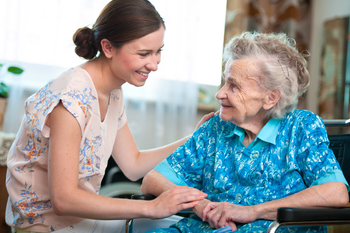 Pflegehilfskraft redet mit Bewohnerin in der stationären Pflege einer Alloheim Senioren-Residenz