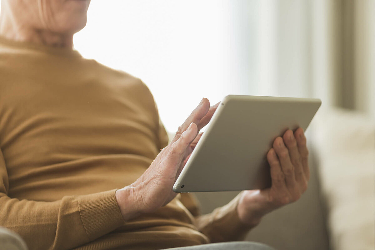 Mann bedient Tablet, um Videotelefonate für Bewohner bei Alloheim Senioren-Residenzen vorzubereiten