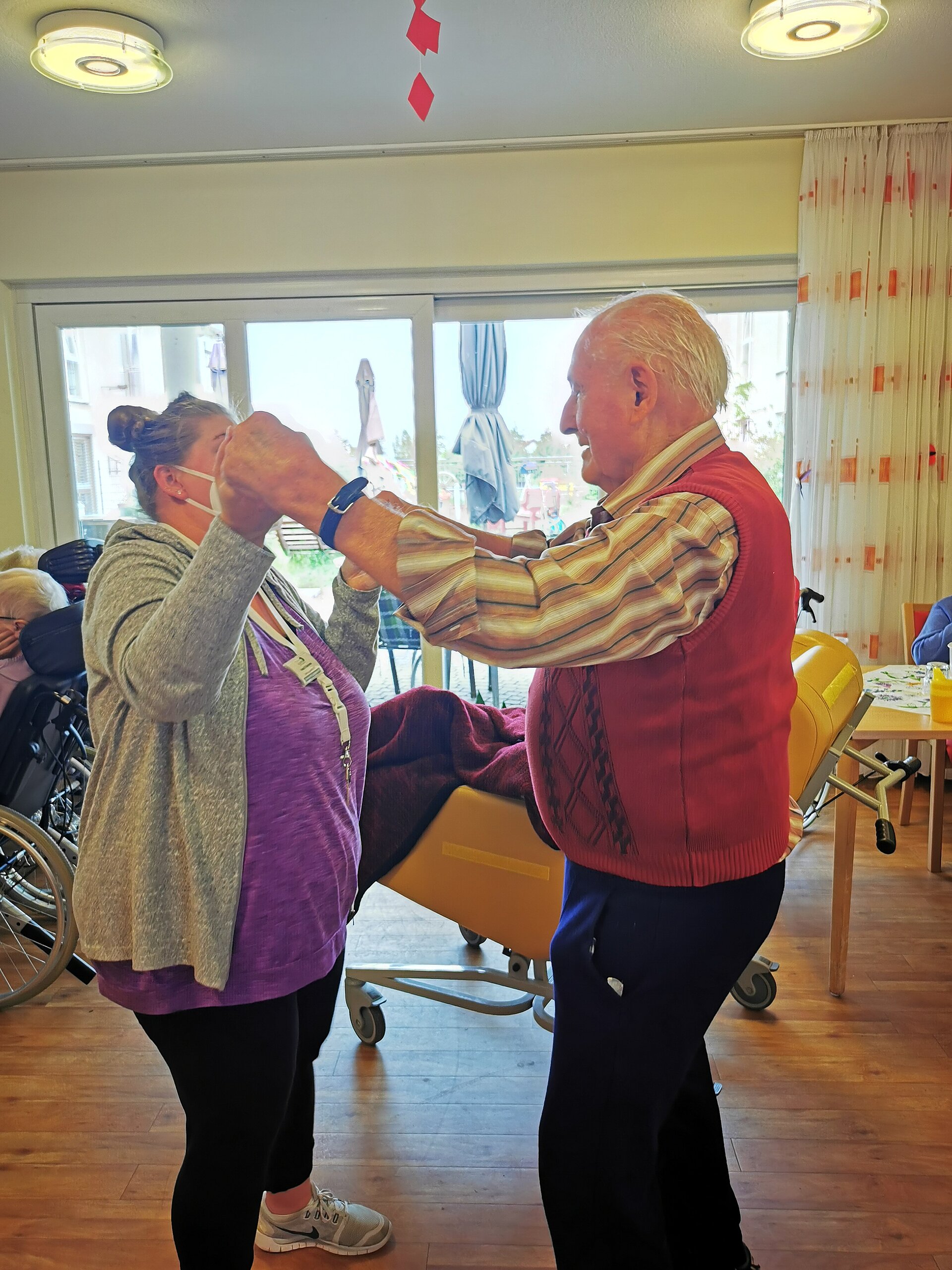 Mitarbeiterin des Sozialen Dienstes tanzt mit Bewohner beim Maifest des Seniorenzentrum AGO Rosbach