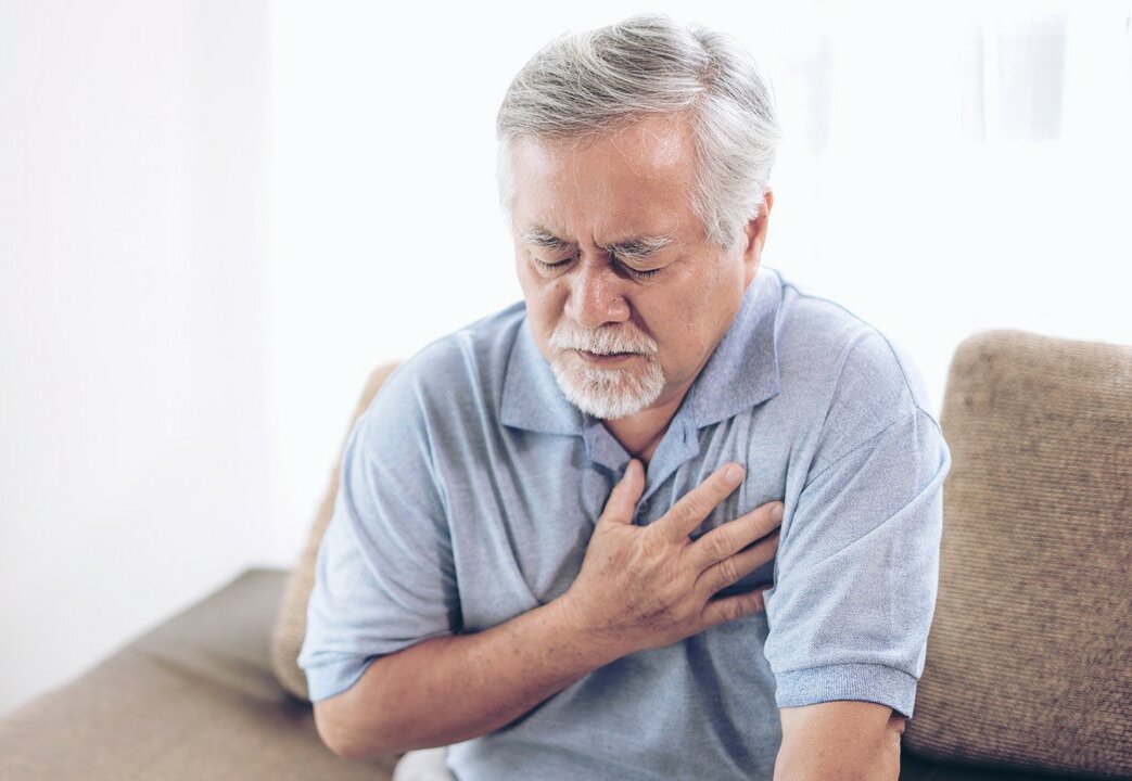 Senior fasst sich schmerzhaft an sein Herz, auf Gefäßerkrankungen macht deshalb der Alloheim Expertenvortrag aufmerksam