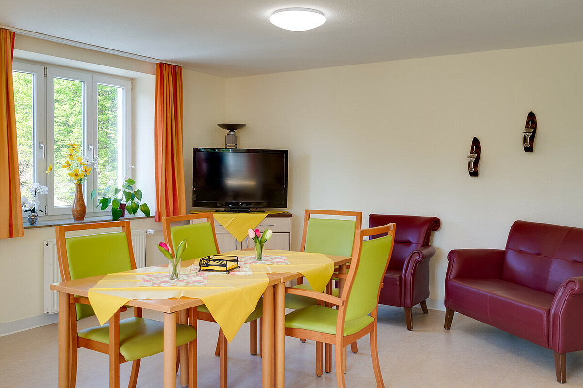 Gemeinschaftsraum mit TV, Sessel und Tisch