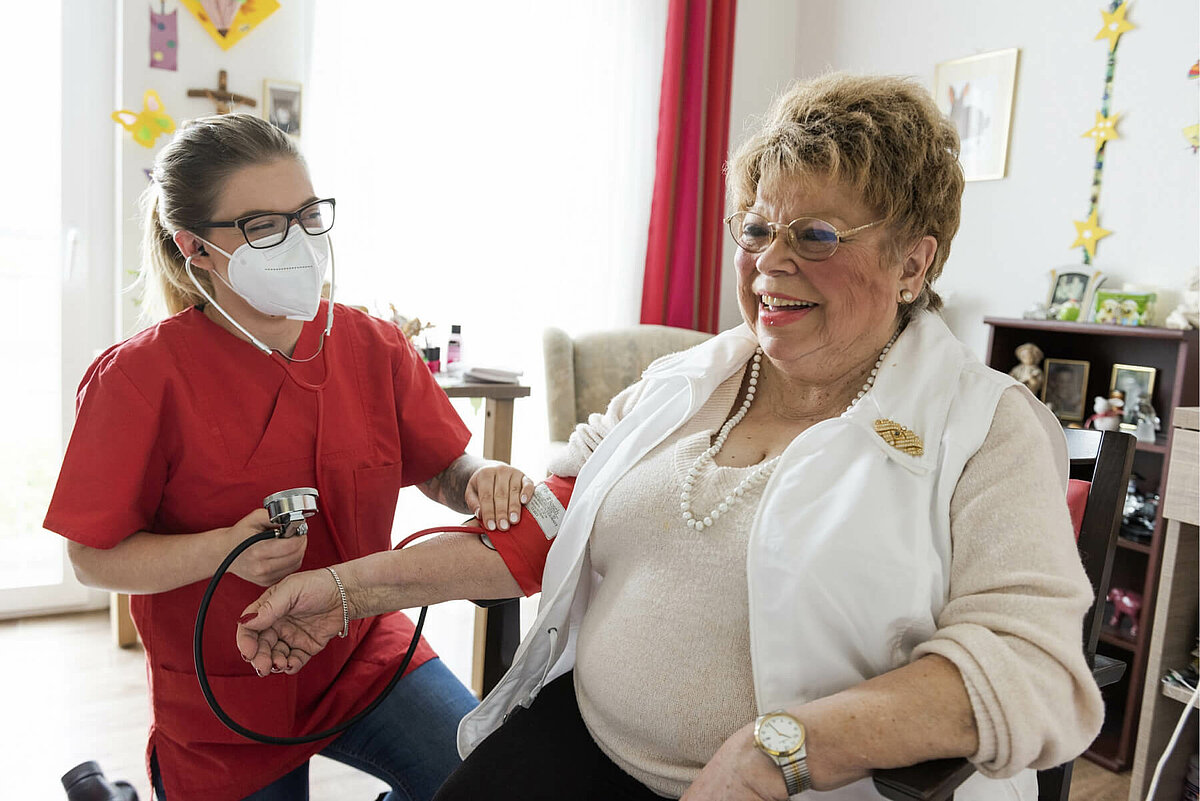 Pflegekraft misst Blutdruck einer Bewohnerin in einer Alloheim Senioren-Residenz