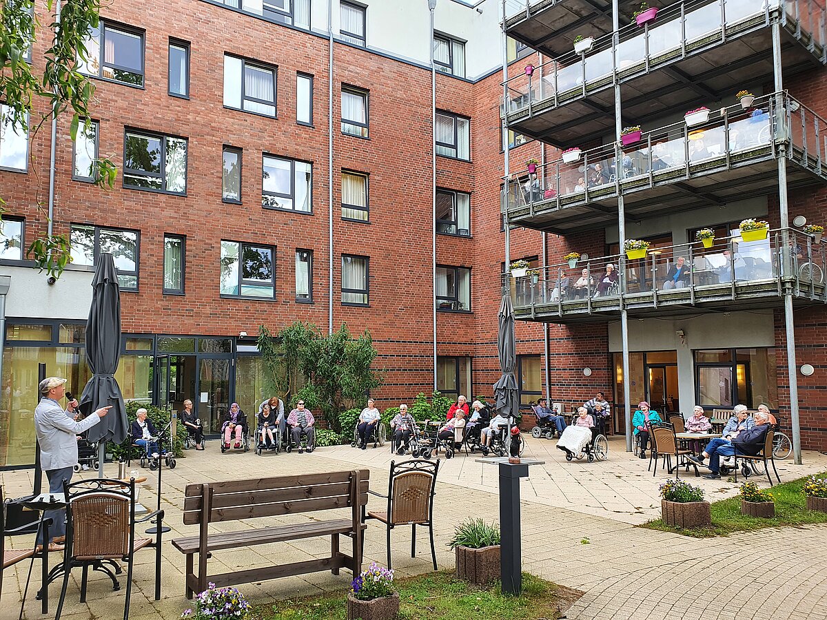 Senioren sitzen auf Terrasse des Seniorenzentrum Kapernaum in Hamburg und lauschen Konzert des Künstlers Oswald