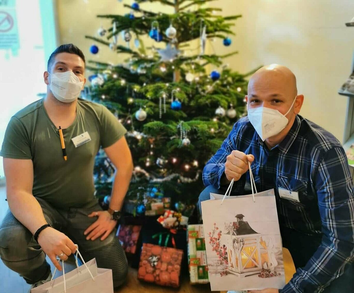 Mitarbeiter des Sozialen Dienstes im Pflegeheim AGO Rosbach mit Geschenketaschen vor dem Weihnachtsbaum