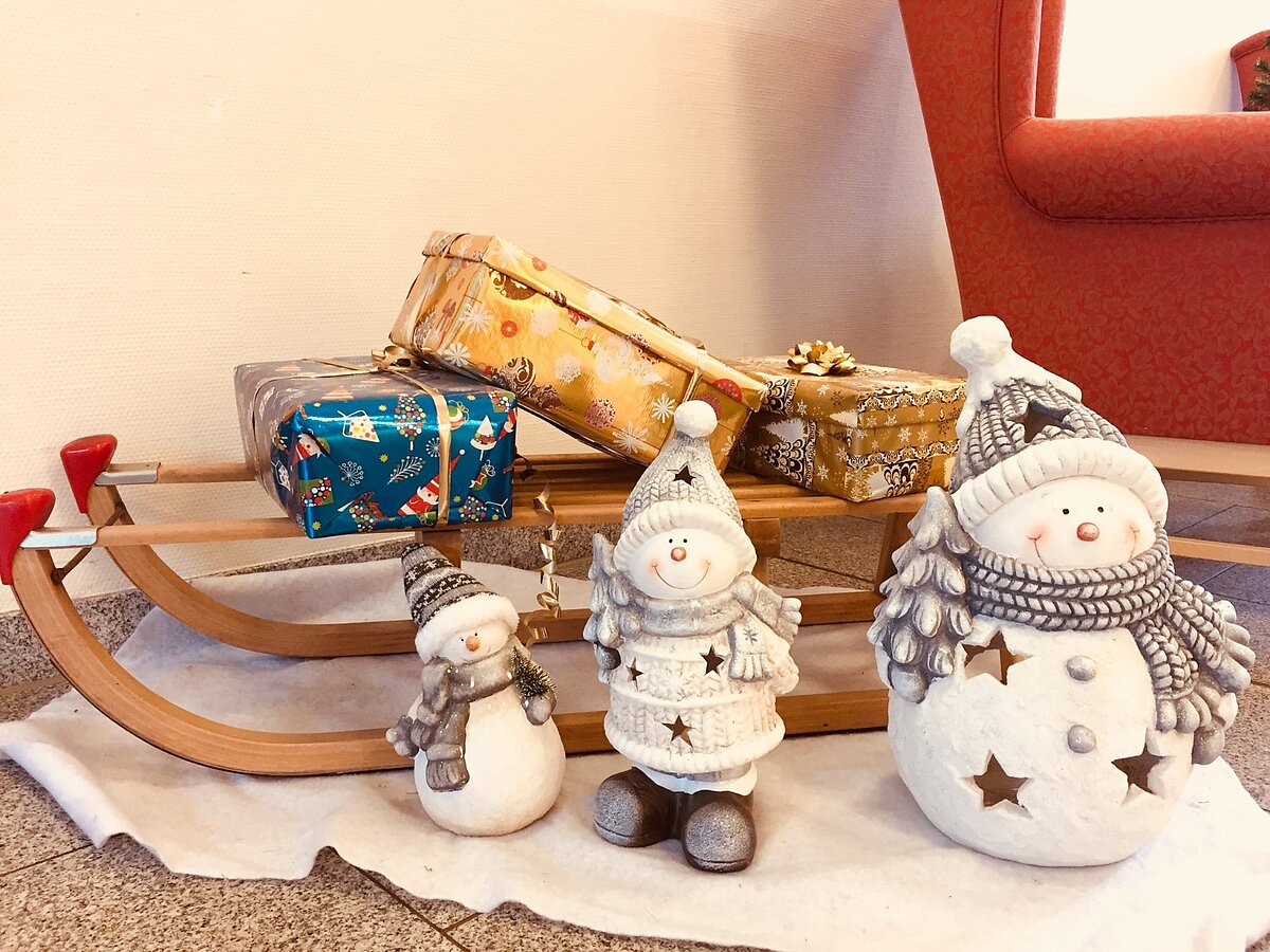 Weihnachtsdekoration mit Schneemann-Figuren und Schlitten mit Geschenken in einer Alloheim Senioren-Residenz