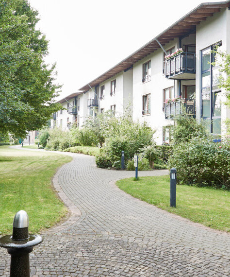 Mieter des Betreuten Wohnens sitzen auf Bank im Garten der Parkresidenz Lünen