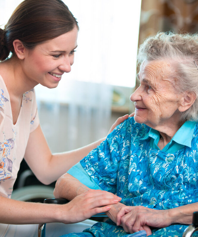 Pflegehilfskraft redet mit Bewohnerin in der stationären Pflege einer Alloheim Senioren-Residenz