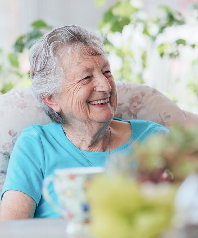 Seniorin sitzt am Gartentisch ihrer Wohnung im Betreuten Wohnen bei Alloheim