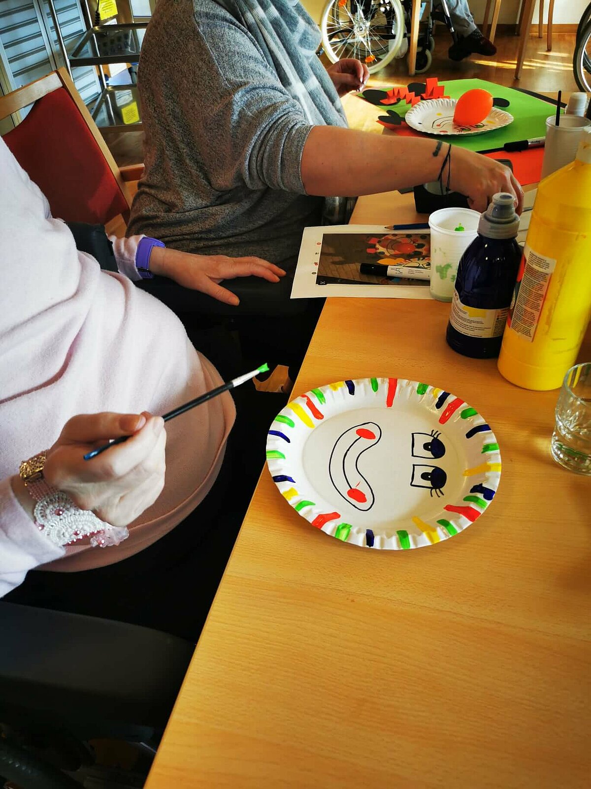 Seniorin bemalt Pappteller als Faschingsdeko für das Seniorenheim "AGO Rosbach"