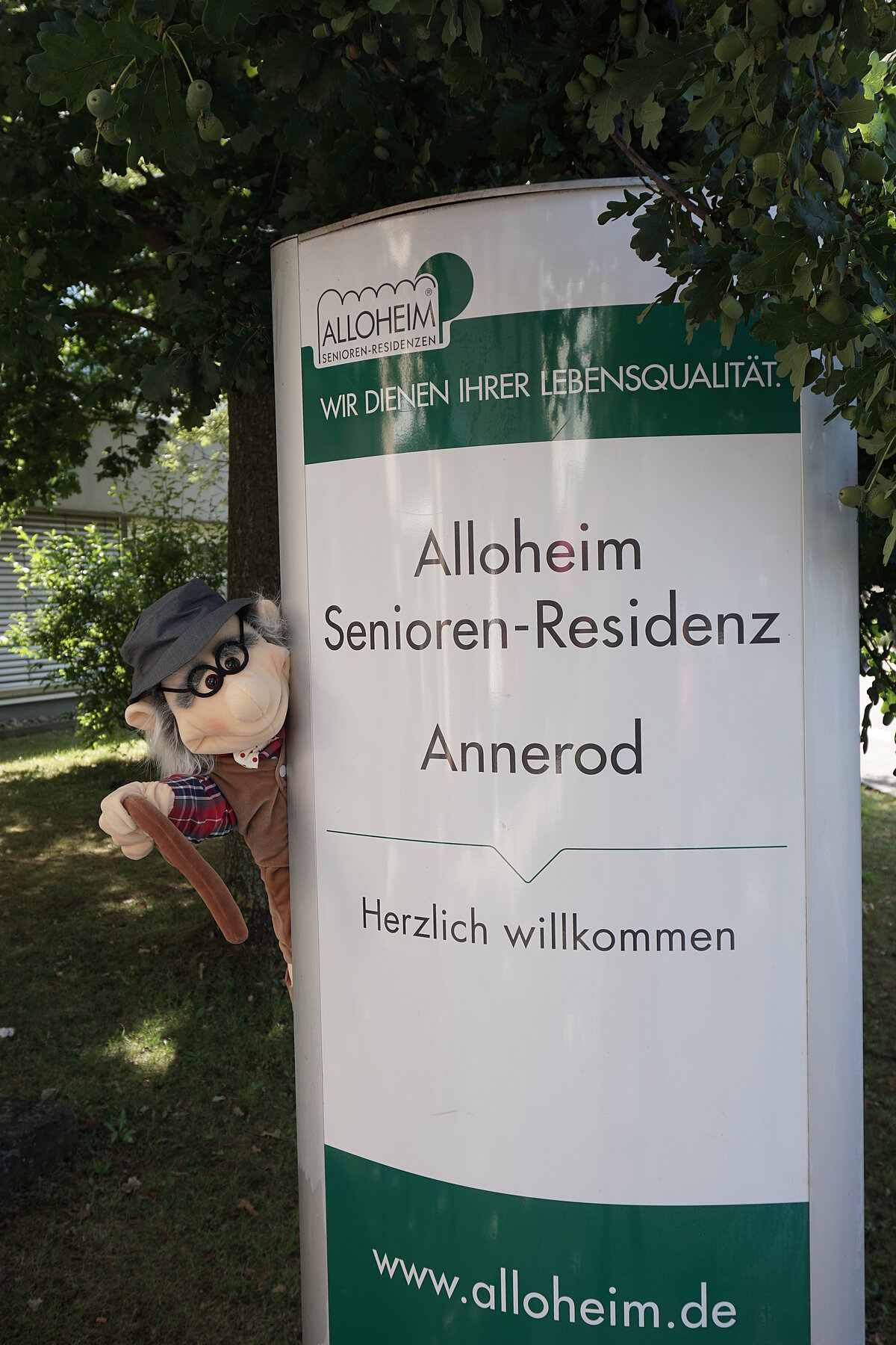 Maskottchen neben dem Schild zur Alloheim Senioren-Residenz Annerod