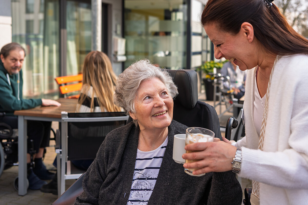 Pflegerin, die einer Seniorin Kaffee bringt