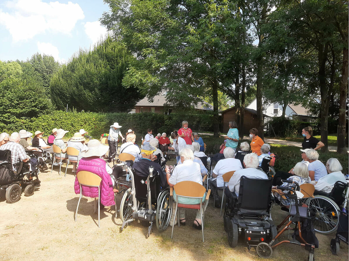 Senioren sitzen gemeinsam bei einem Ausflug im sonnigen Park