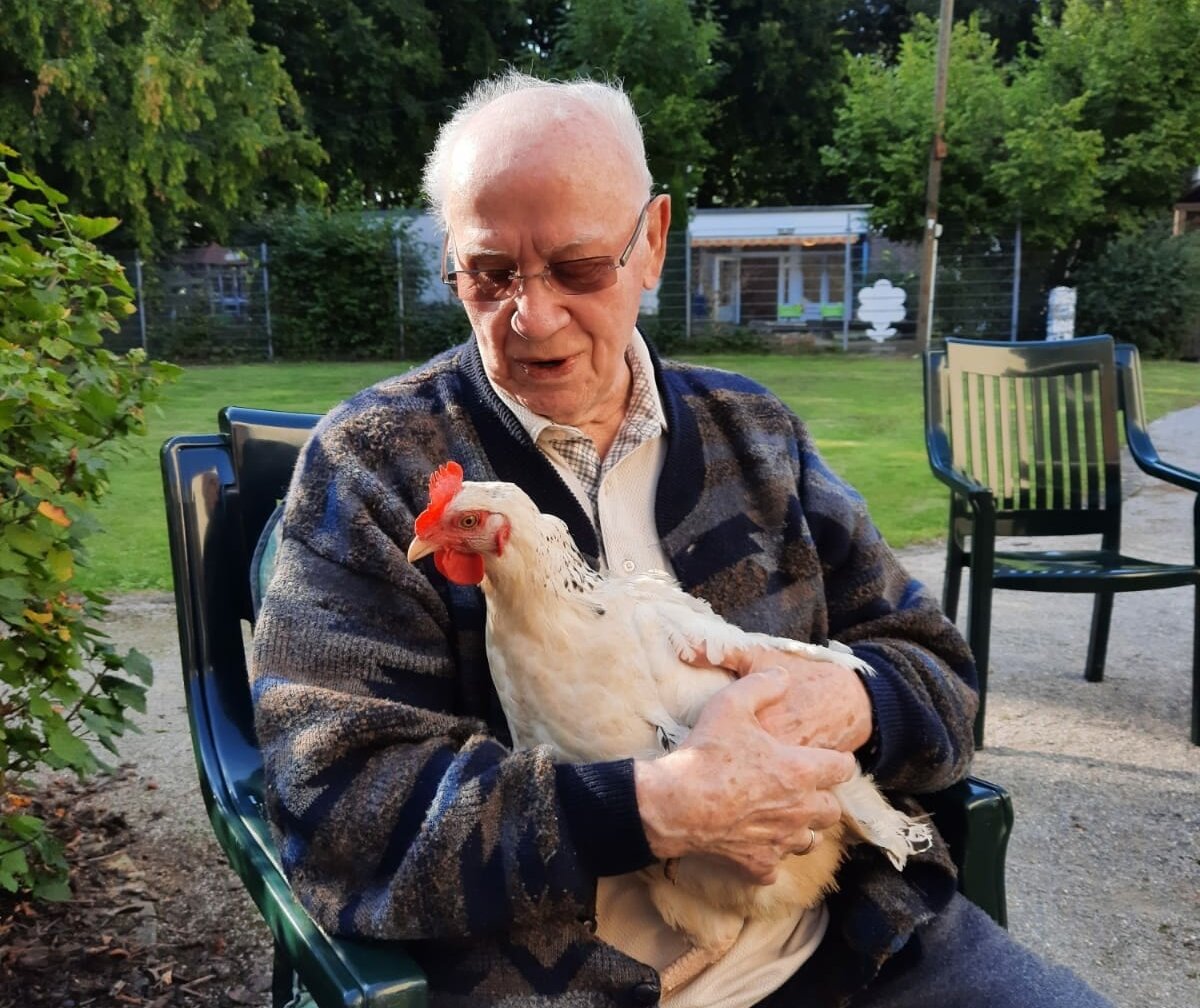 Huhn sitzt auf Schoß eines Senioren des Jakobus-Stift An der Kreuzkirche in Hamm