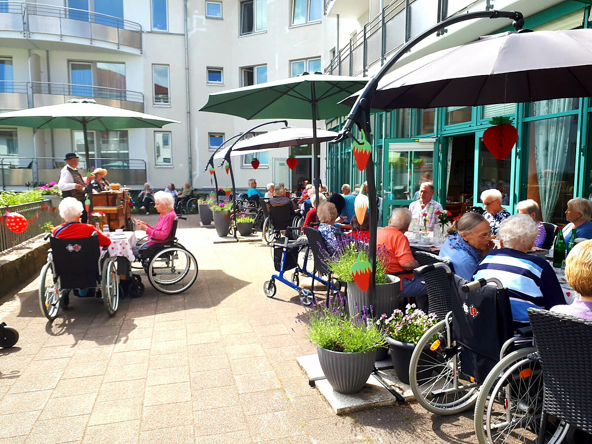 Bewohner des Pflegeheims Lübeck gemeinsam auf der Terrasse beim Erdbeerfest