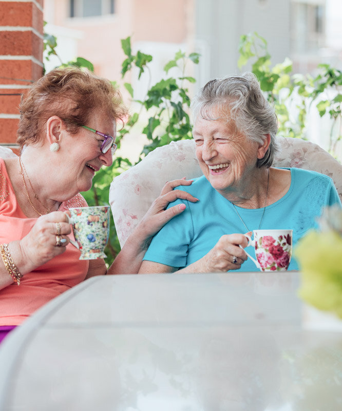 Seniorinnen trinken Tee auf der Terrasse einer Alloheim Senioren-Residenz