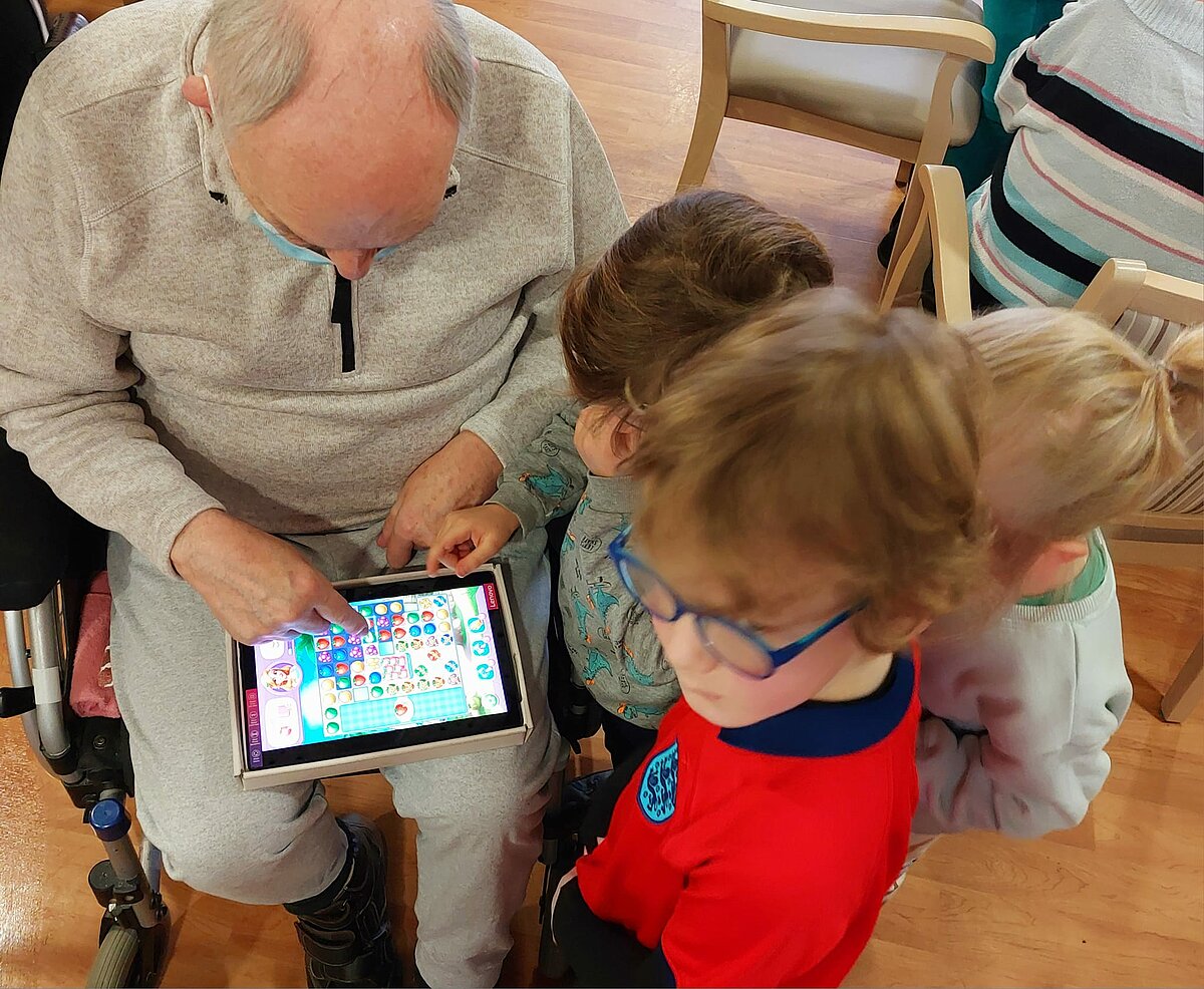 Kita Kinder und Bewohner spielen Tablet