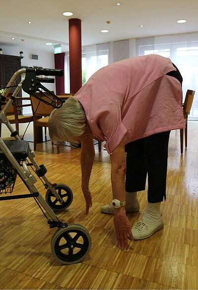 Seniorin bückt sich mit den Fingerspitzen bis zum Boden