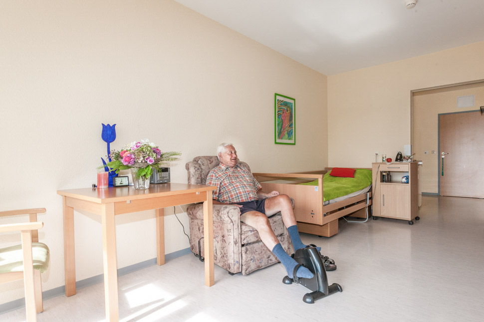 Bewohner fährt auf Home-Trainer Fahrrad in seinem Zimmer der Alloheim Senioren-Residenz Am Kurpark in Bad Marienberg