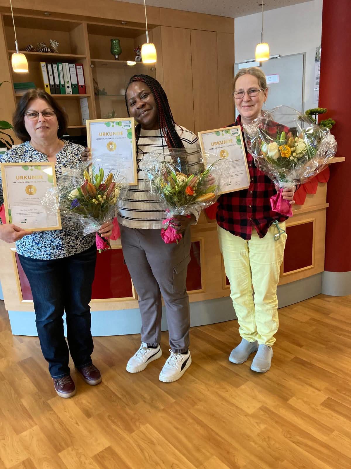 Mitarbeiter mit Blumen und Urkunden