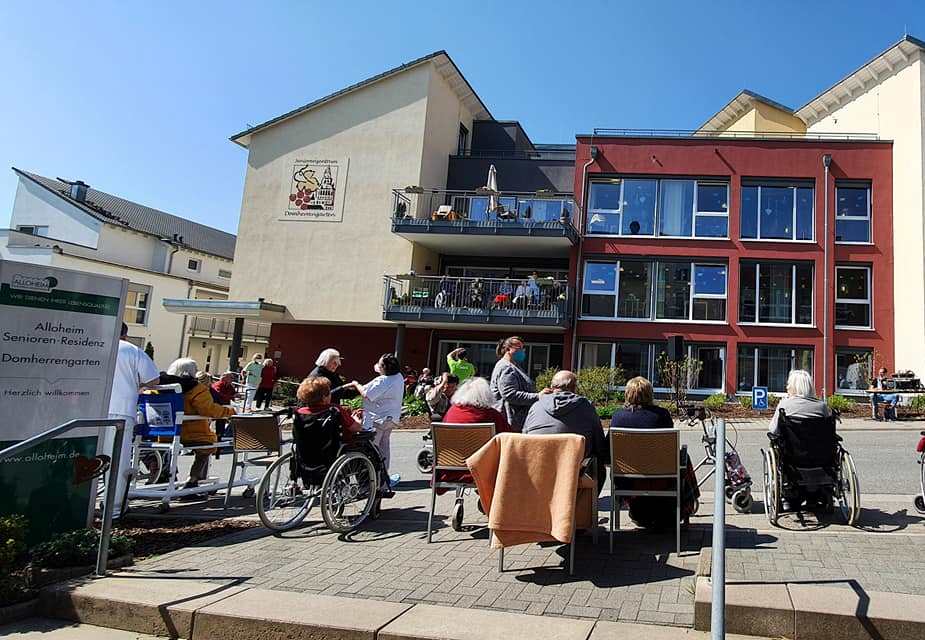 Bewohner sitzen vor der Alloheim Senioren-Residenz "Domherrengarten" in Essenheim beim Frühlingsfest