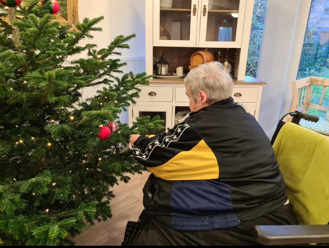 Bewohnerin schmückt den Weihnachtsbaum im Günters Saal der Einrichtung.
