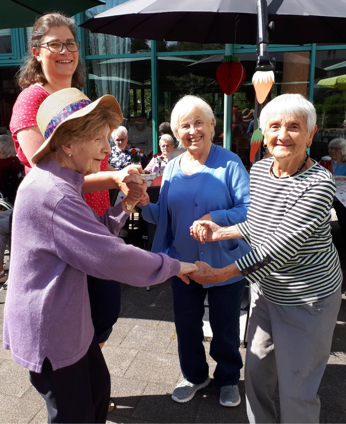 Seniorinnen tanzen gemeinsam beim Erdbeerfest im Altenheim