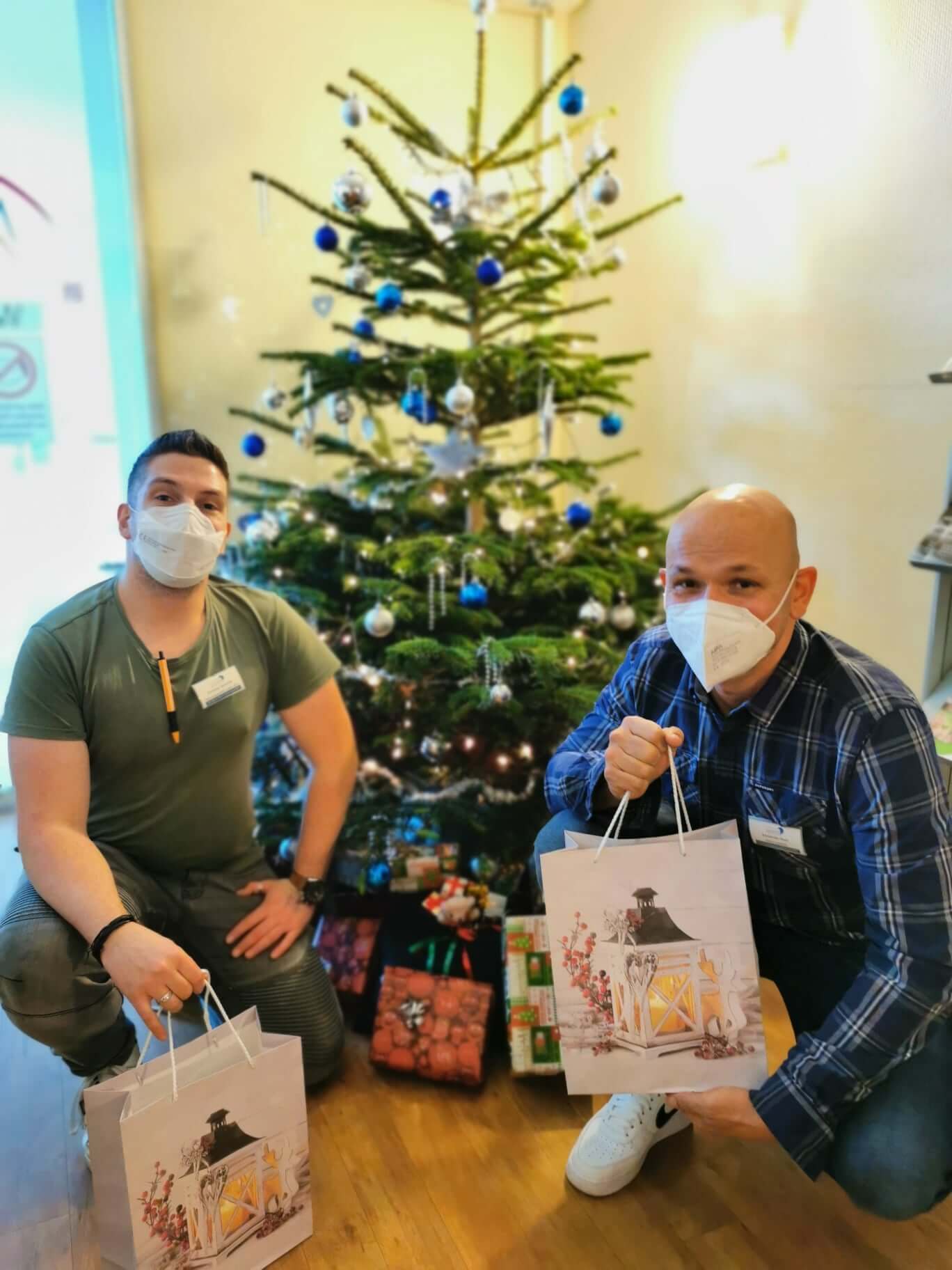 Mitarbeiter des Sozialen Dienstes im Pflegeheim AGO Rosbach mit Geschenketaschen vor dem Weihnachtsbaum