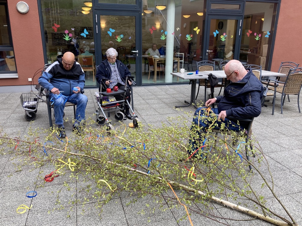 Drei Bewohner schmücken gemeinsam den Maibaum des Pflegeheims Sundern