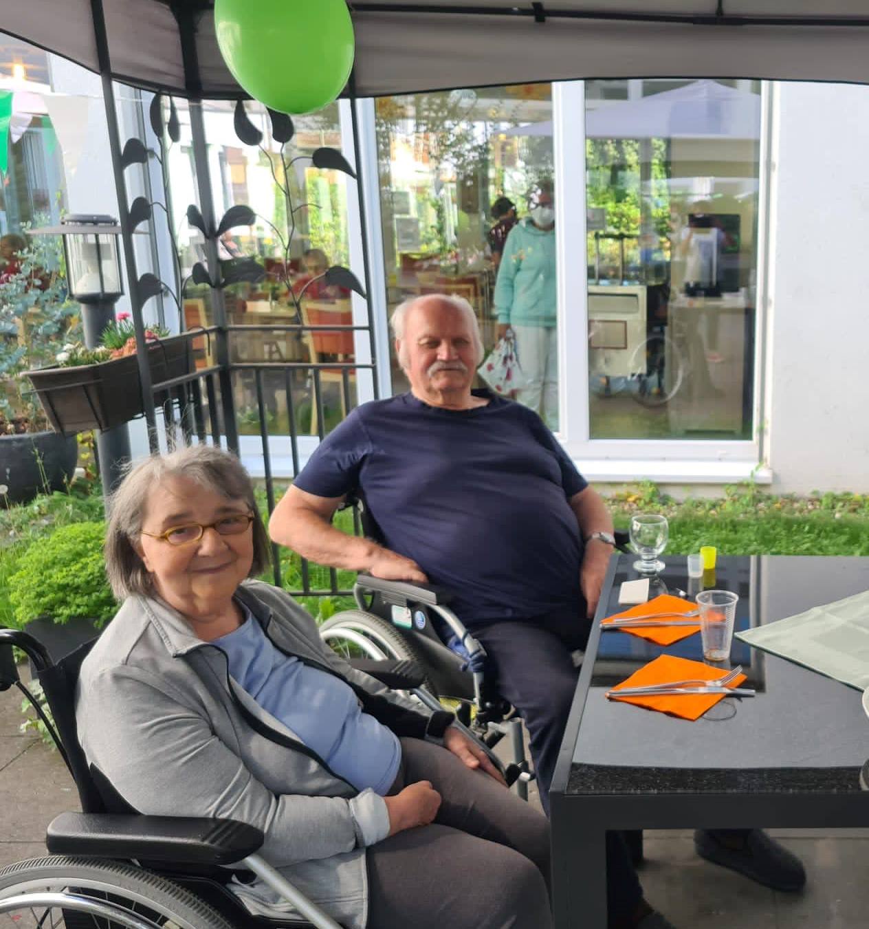 Bewohner sitzen während des Grillfests auf der Terrasse des Seniorenzentrums AGO Trier
