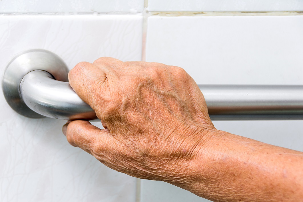 Seniorin hält sich am Haltegriff fest