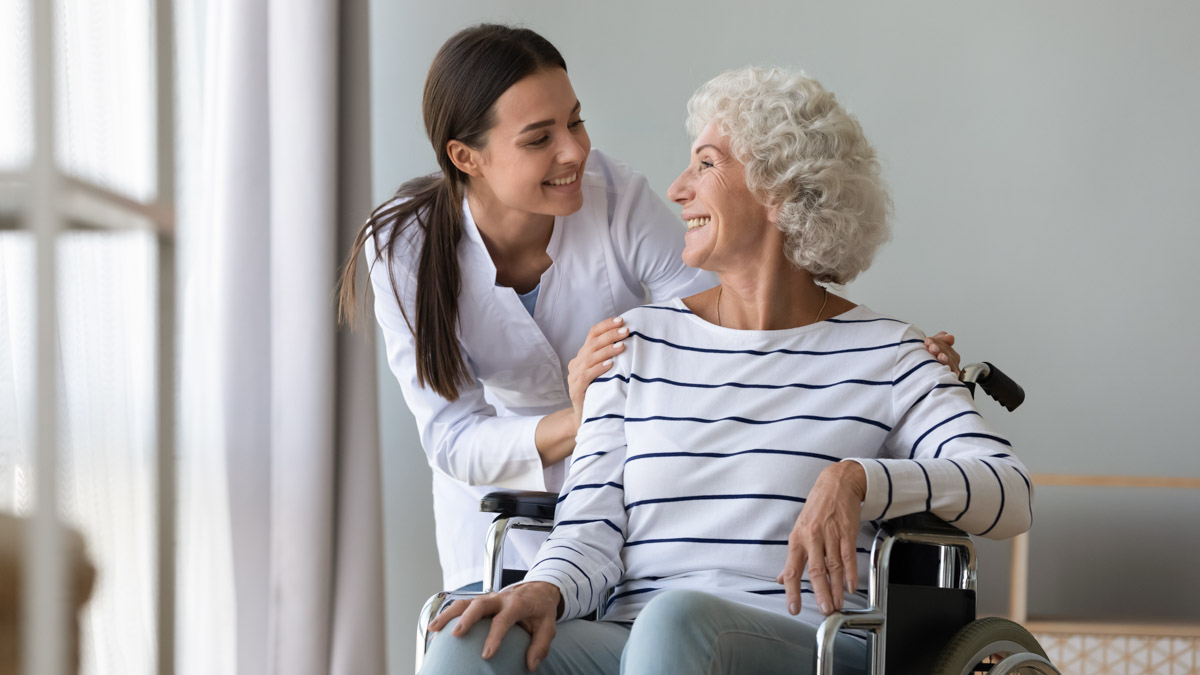 Seniorin im Rollstuhl mit einer Pflegerin in einer Alloheim Senioren-Residenz